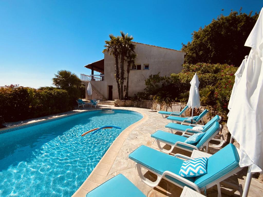 - une piscine avec des chaises longues et des parasols bleus dans l'établissement La Maison de Laurence, aux Issambres