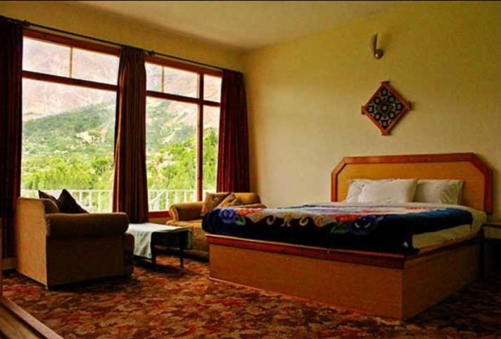 a bedroom with a bed and a large window at Hilltop Hotel in Hunza Valley