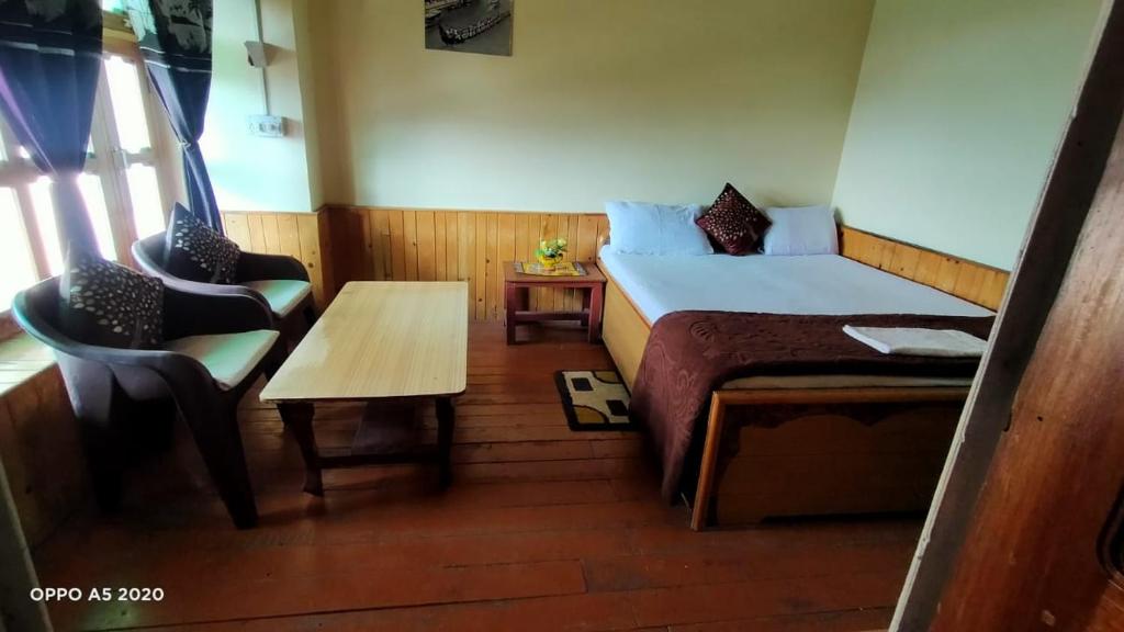 a small room with a bed and a table and a chair at Ritu Raj Home Stay & Cafe in Malther