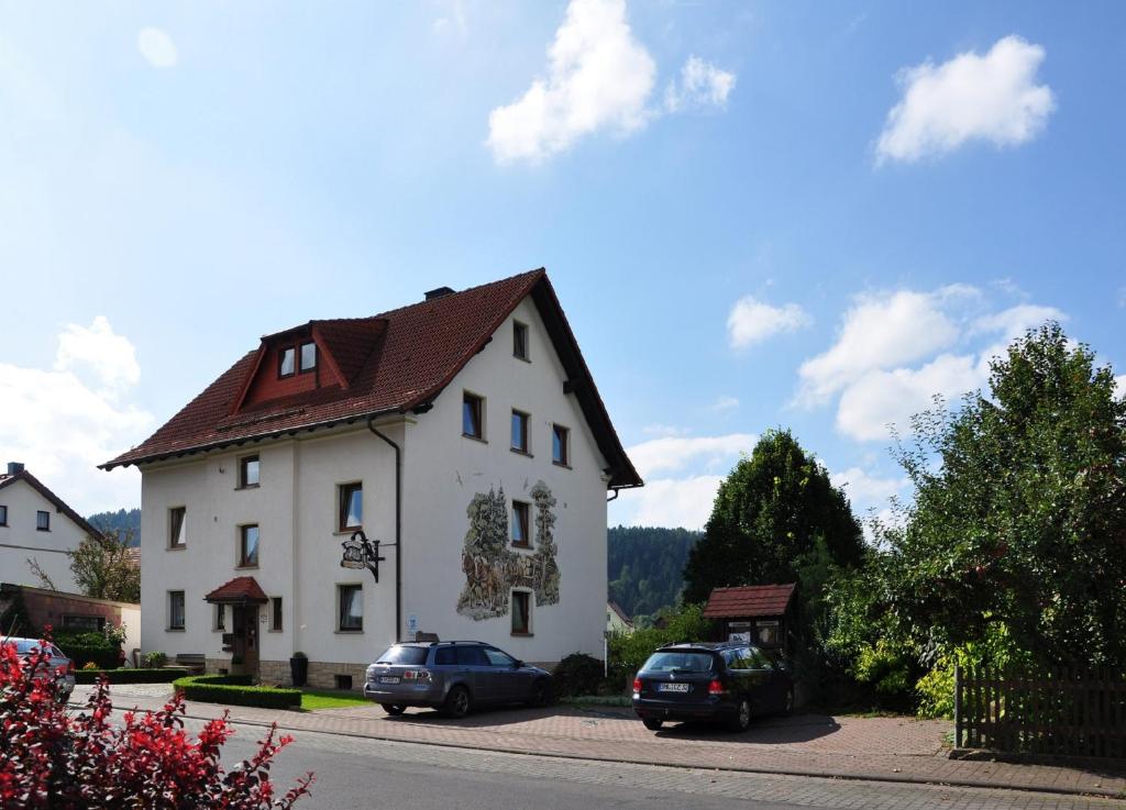 ein großes weißes Haus mit Autos auf einer Straße geparkt in der Unterkunft Landhotel Zur Pferdetränke in Schleid