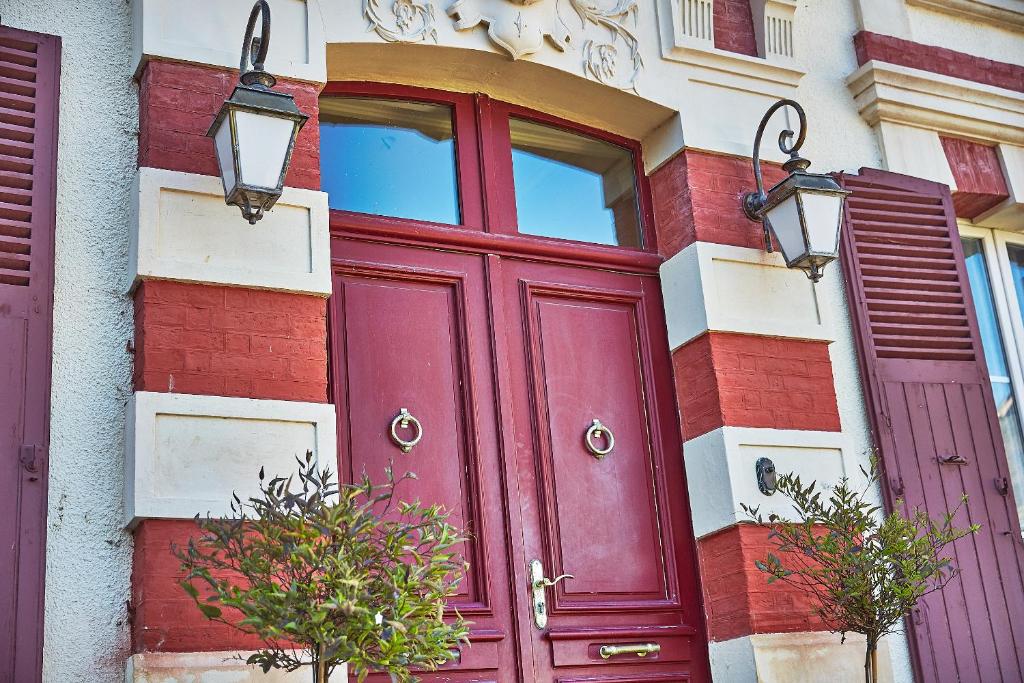 a red door on the side of a building at Demeure de Manneville - SPA - 1Km des plages de Cabourg in Dives-sur-Mer