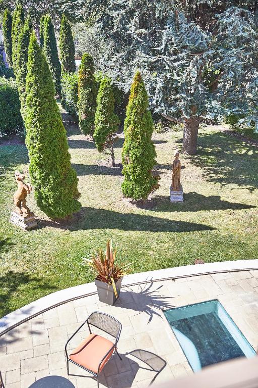 a garden with a chair and trees and a pool at Demeure de Manneville - SPA - 1Km des plages de Cabourg in Dives-sur-Mer