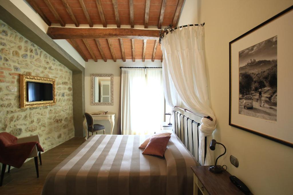 a bedroom with a bed and a window and a desk at Molino Di Foci in San Gimignano