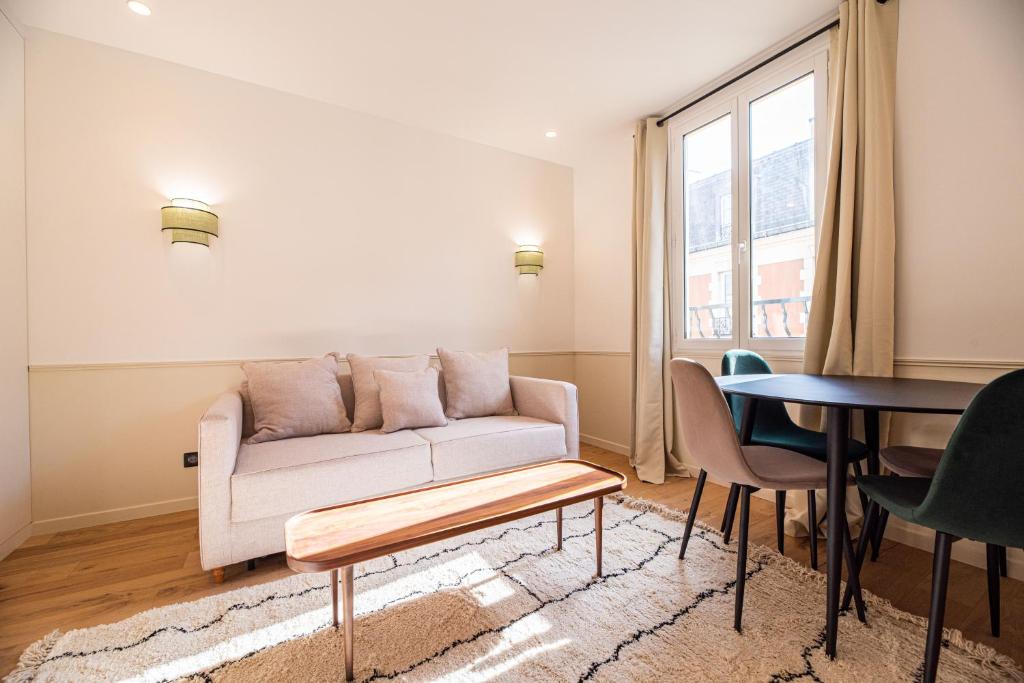 a living room with a couch and a table at Vignature residence in Asnières-sur-Seine