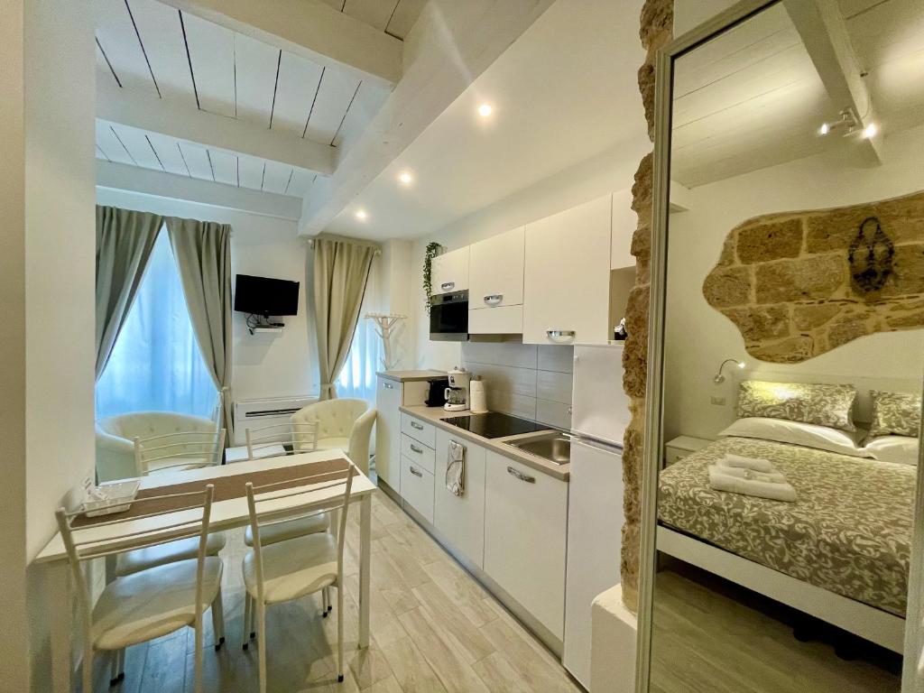 a small room with a bed and a desk and a kitchen at Protea House in Alghero