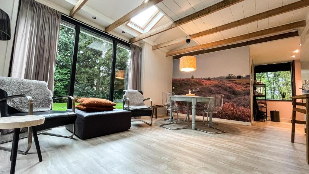 ein Wohnzimmer mit einem Tisch, Stühlen und Fenstern in der Unterkunft Vossenbelt in Gasselte