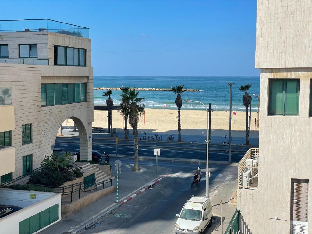 een uitzicht op een strand met een auto op straat bij Miraks HaRav Kuk in Tel Aviv