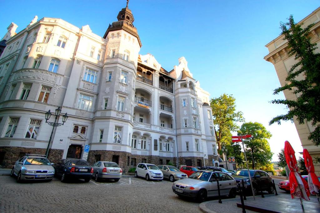 un grand bâtiment avec des voitures garées devant lui dans l'établissement Bishop Apartments, à Brno
