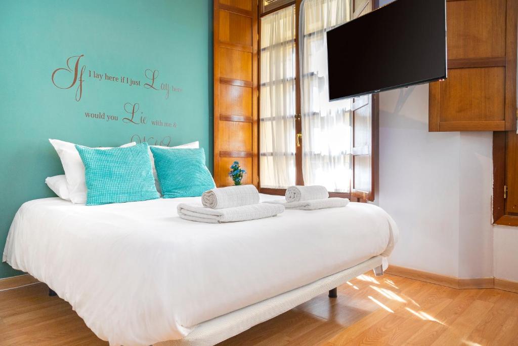 1 dormitorio con 1 cama blanca y TV de pantalla plana en Livemalaga Clemens, en Málaga