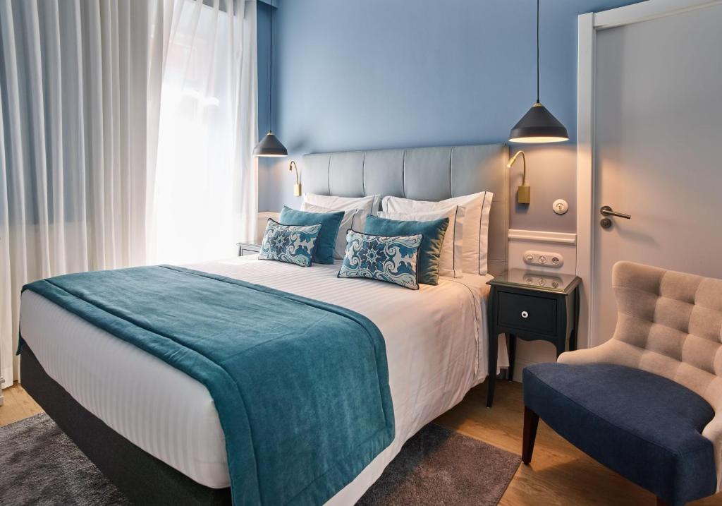 una camera con un grande letto e una sedia di Residencial Florescente a Lisbona