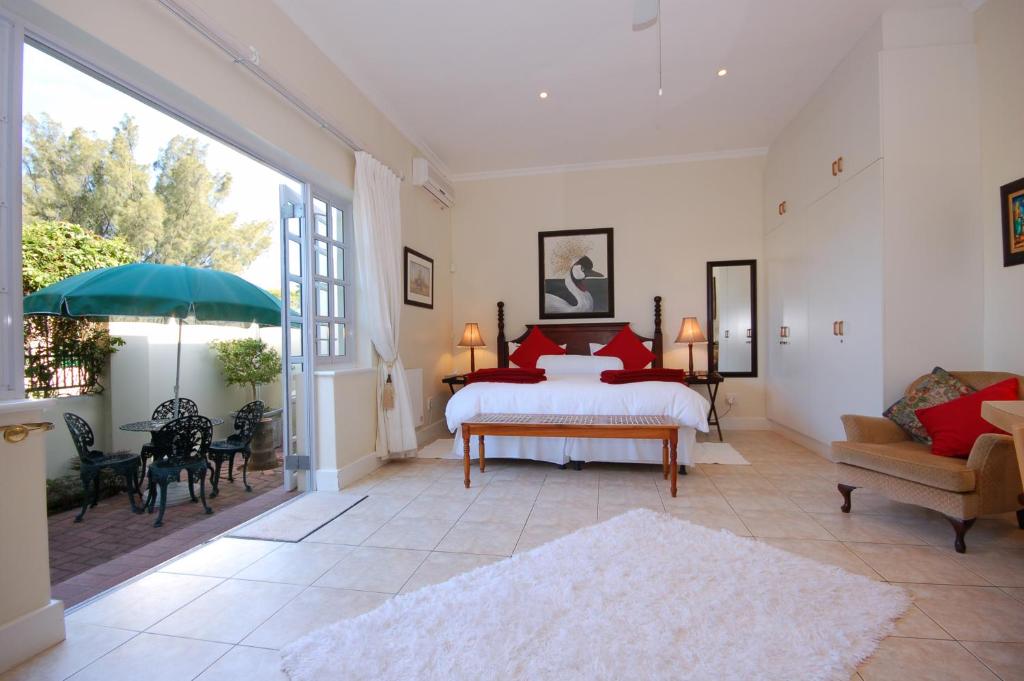 a bedroom with a bed with red pillows at Anchorage Guesthouse in Port Elizabeth