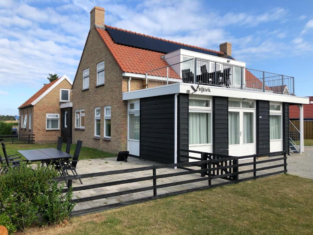 a house with a deck and a table in front of it at De Vrije wil in Buren