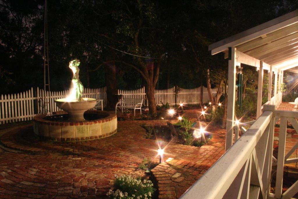 a patio with a fountain and a fence at night at Rosebridge House Bed & Breakfast Adult Retreat in Gooseberry Hill