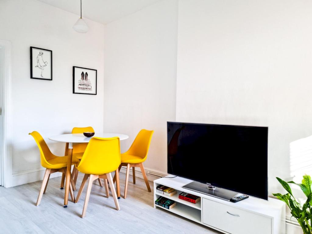 ein Wohnzimmer mit einem Tisch und gelben Stühlen in der Unterkunft Pass The Keys Beautiful 2 Bedroom Apartment in Wimbledon in London