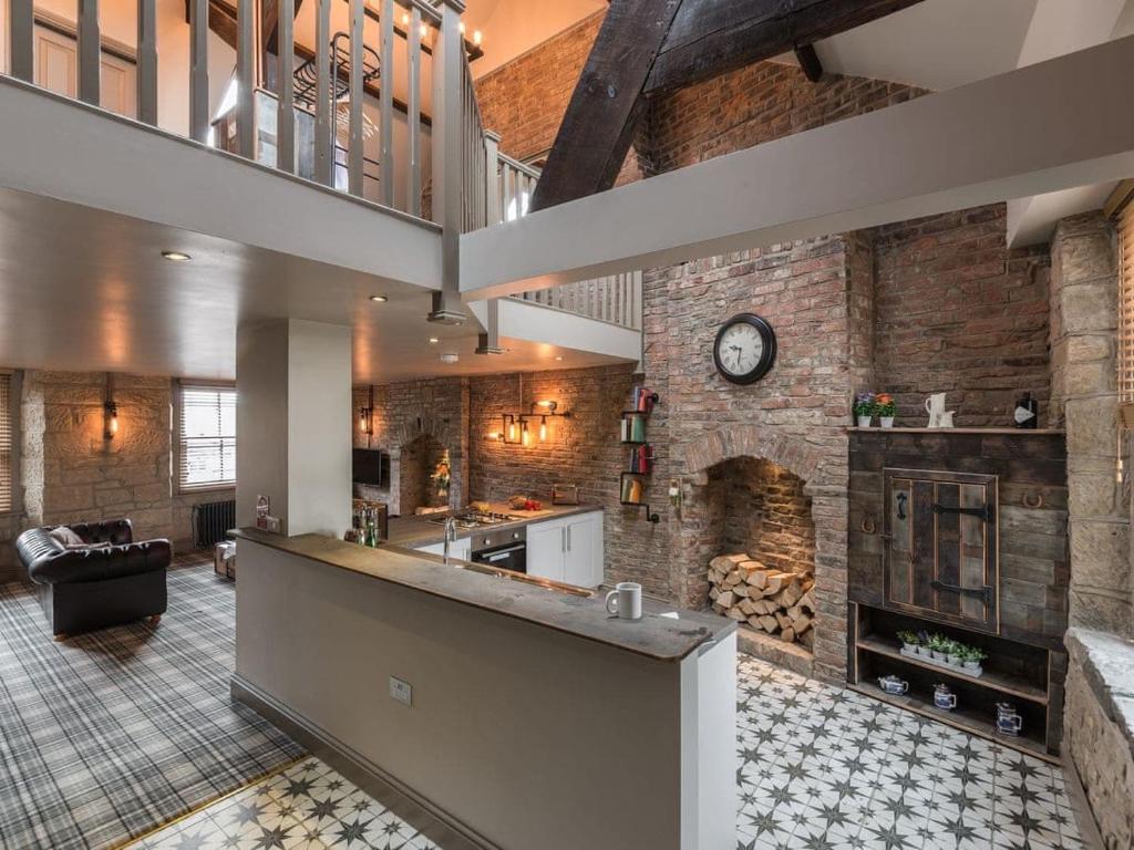 a large kitchen with a brick wall with a fireplace at Newgate Loft in Morpeth