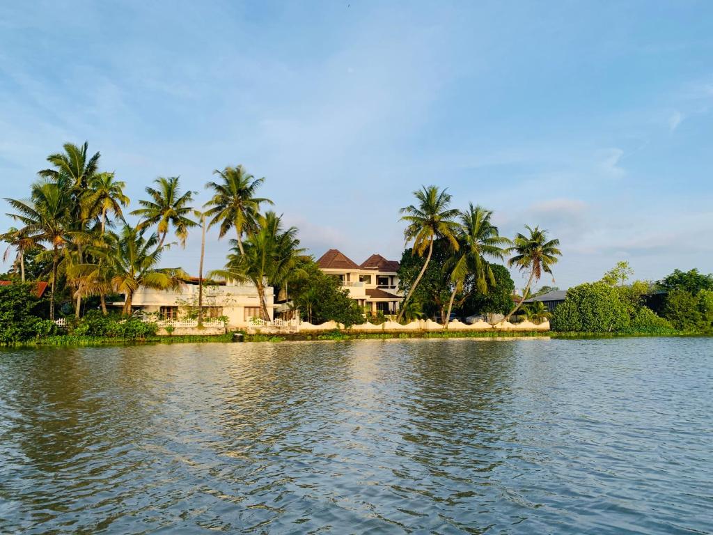 uma casa na margem de um lago com palmeiras em BluSalzz Villas - The Ambassador's Residence, Kochi - Kerala em Cochin