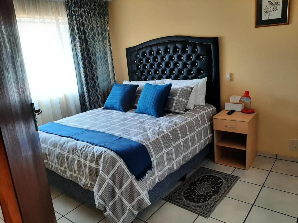 a bedroom with a bed with blue pillows and a window at TM Self Catering Accommodation in Middelburg