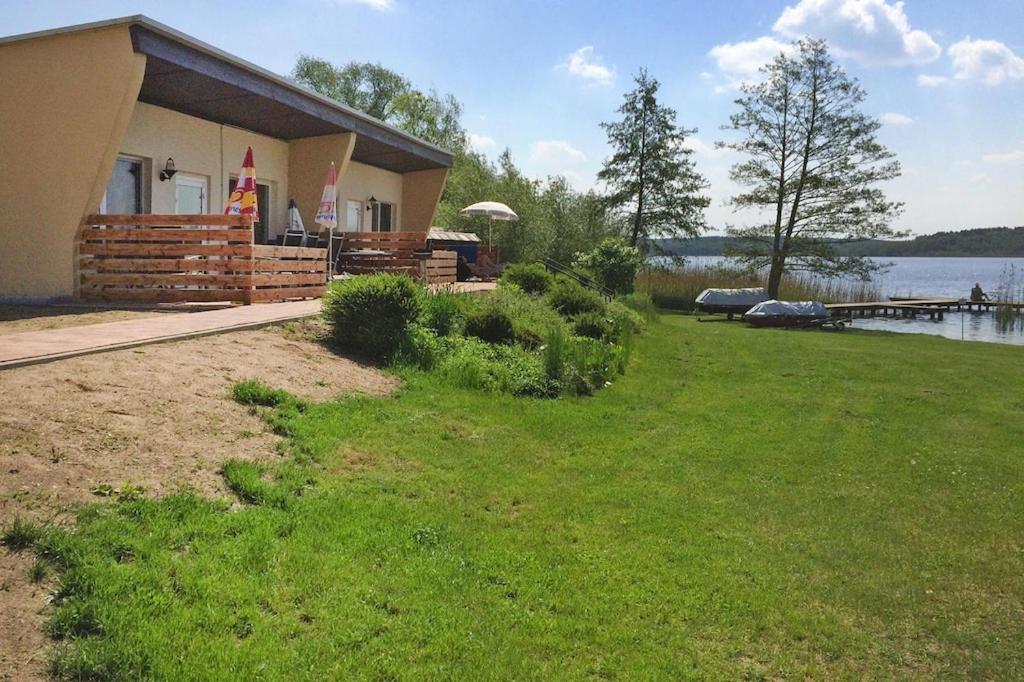 a house with a grassy yard next to a lake at Double bungalow at the Groß Labenzer See, Klein Labenz in Klein Labenz