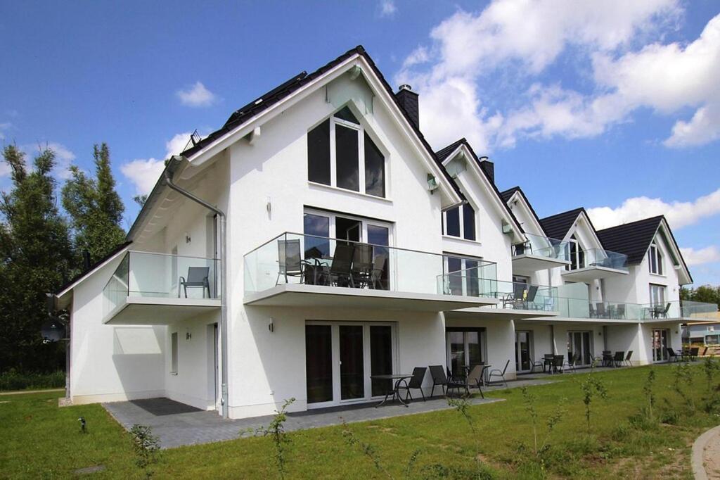 una gran casa blanca con sillas en el césped en Terraced house harbor flair at the Plauer See, Plau am See en Plau am See