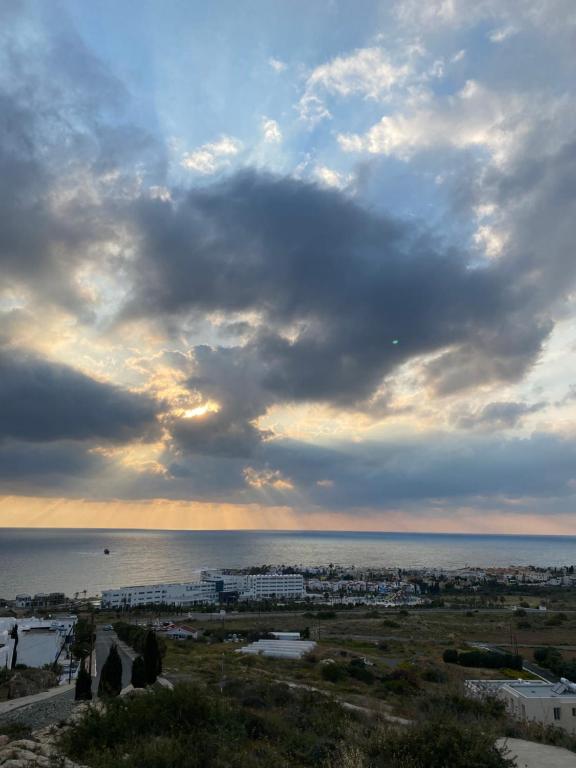 einen wolkigen Himmel über das Meer und eine Stadt in der Unterkunft Melania Gardens Apartment in Klorakas