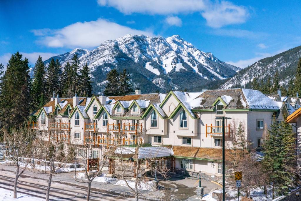 a large building with snow covered mountains in the background at The Rundlestone Lodge in Banff