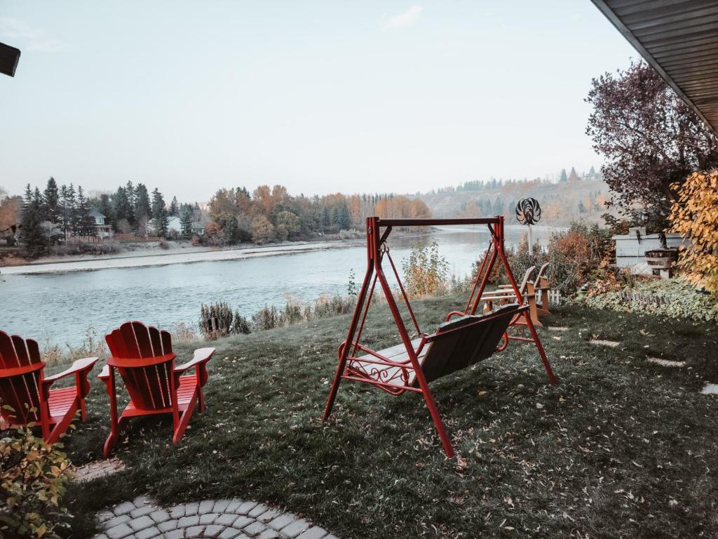 two chairs and a swing next to a river at Along River Ridge in Calgary