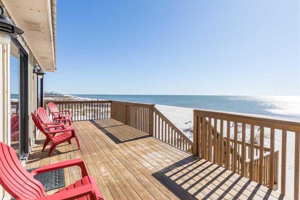 eine Terrasse mit roten Stühlen und Strand in der Unterkunft Heavenly Days by Meyer Vacation Rentals in Fort Morgan