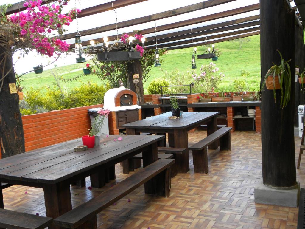 un patio avec des tables et des bancs en bois dans un jardin dans l'établissement Hacienda Rosas Pamba, à Otavalo