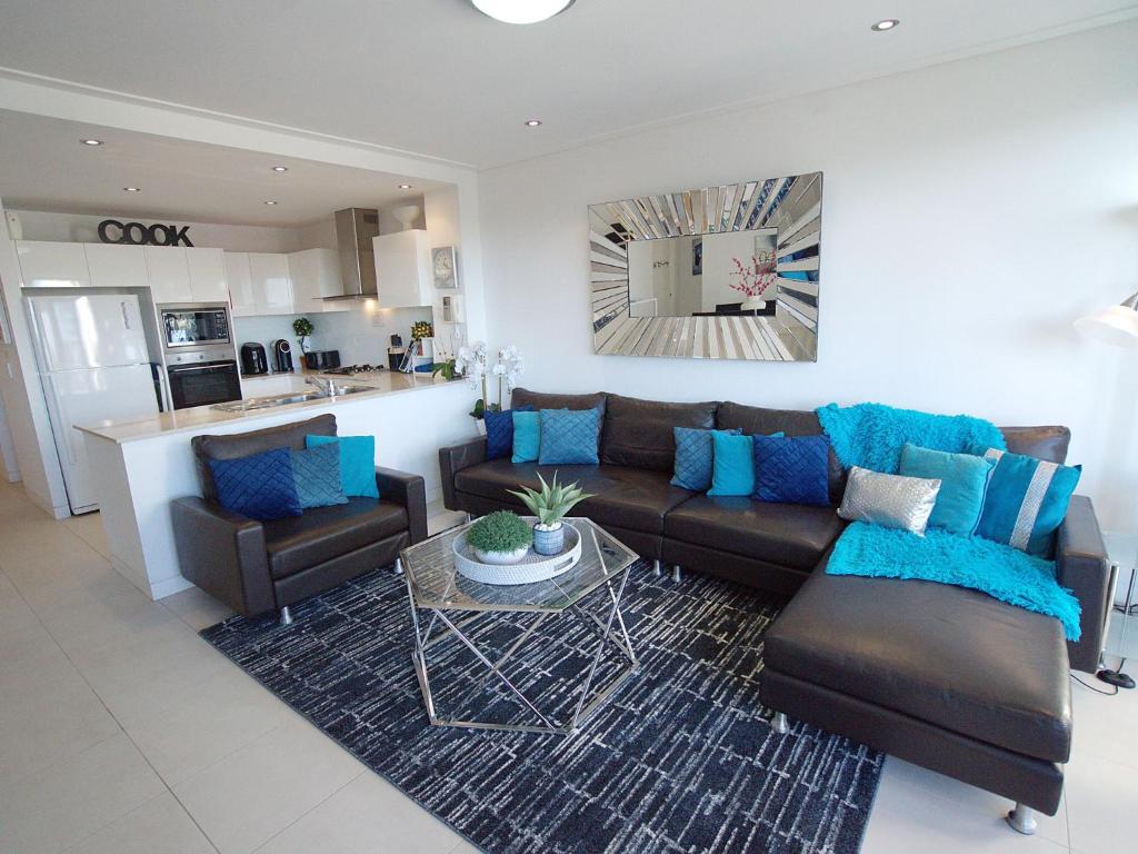 a living room with a brown couch and blue pillows at Blue Coral Terrace Coast Luxury 31 in The Entrance