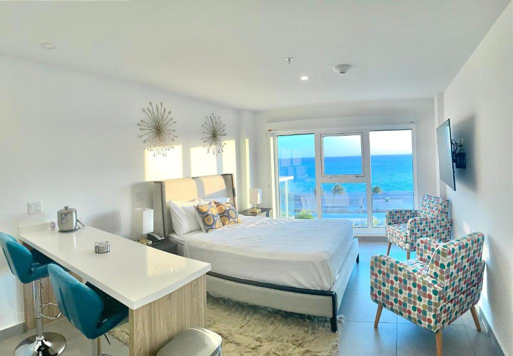Schlafzimmer mit einem Bett, einem Schreibtisch und Stühlen in der Unterkunft Ocean View Condo overlooking the Caribbean Sea in Oranjestad