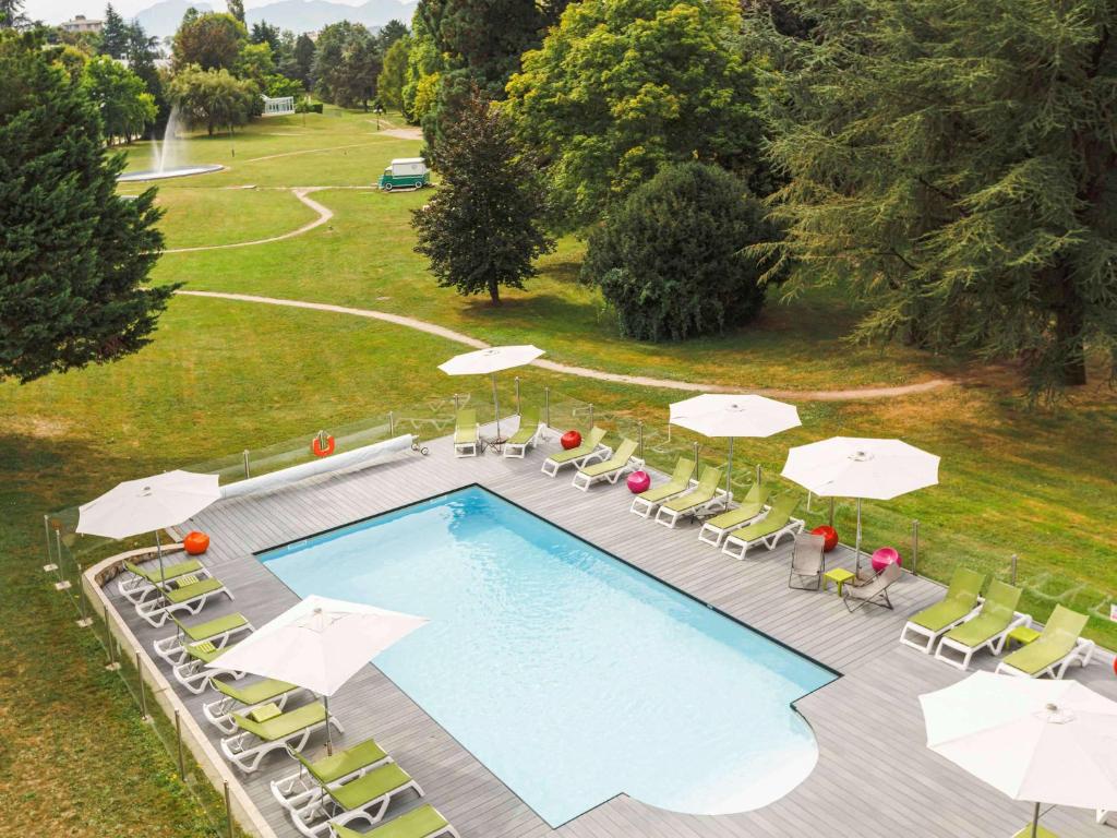 a pool with a pool table, chairs and umbrellas at ibis Styles Aix les Bains Domaine de Marlioz in Aix-les-Bains