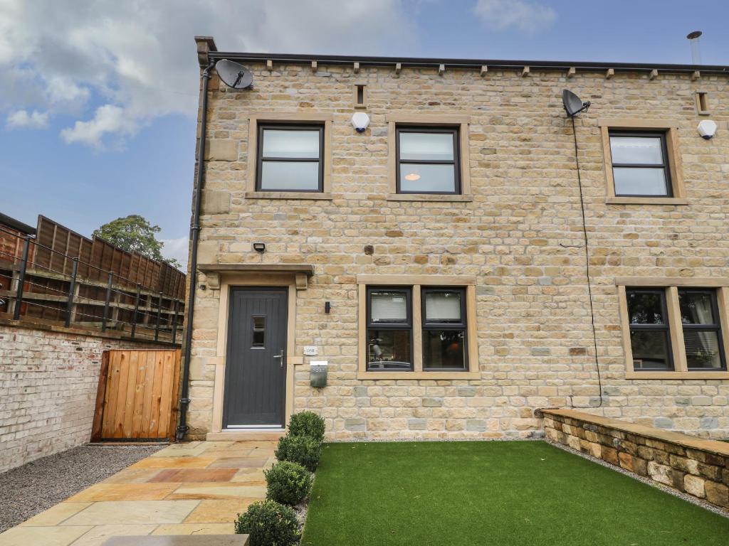 a brick house with a lawn in front of it at 1 Stansfield Mews in Keighley