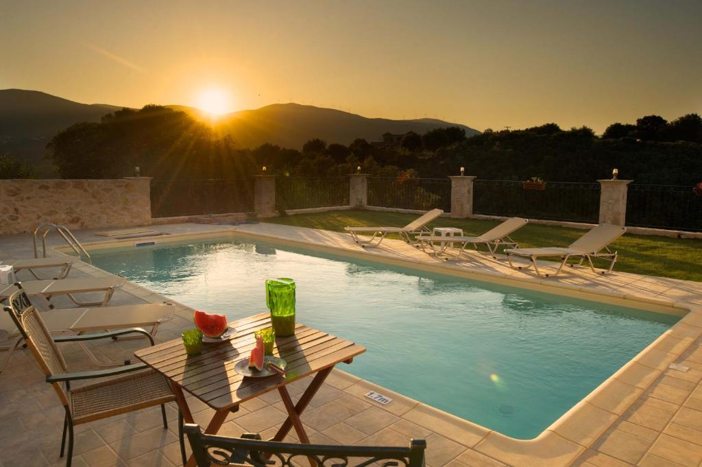 a pool with chairs and a table and the sunset at superb villa with private pool peaceful location in Sami