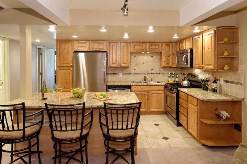 a kitchen with wooden cabinets and a large island with bar stools at Standard Two Bedroom - Aspen Alps #103 in Aspen