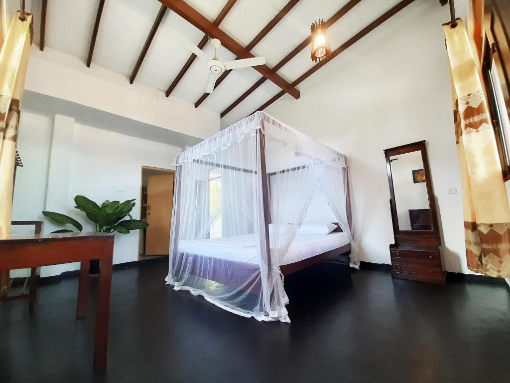 a bedroom with a bed with a mosquito net at Sunstyle Mirissa Guest House in Mirissa