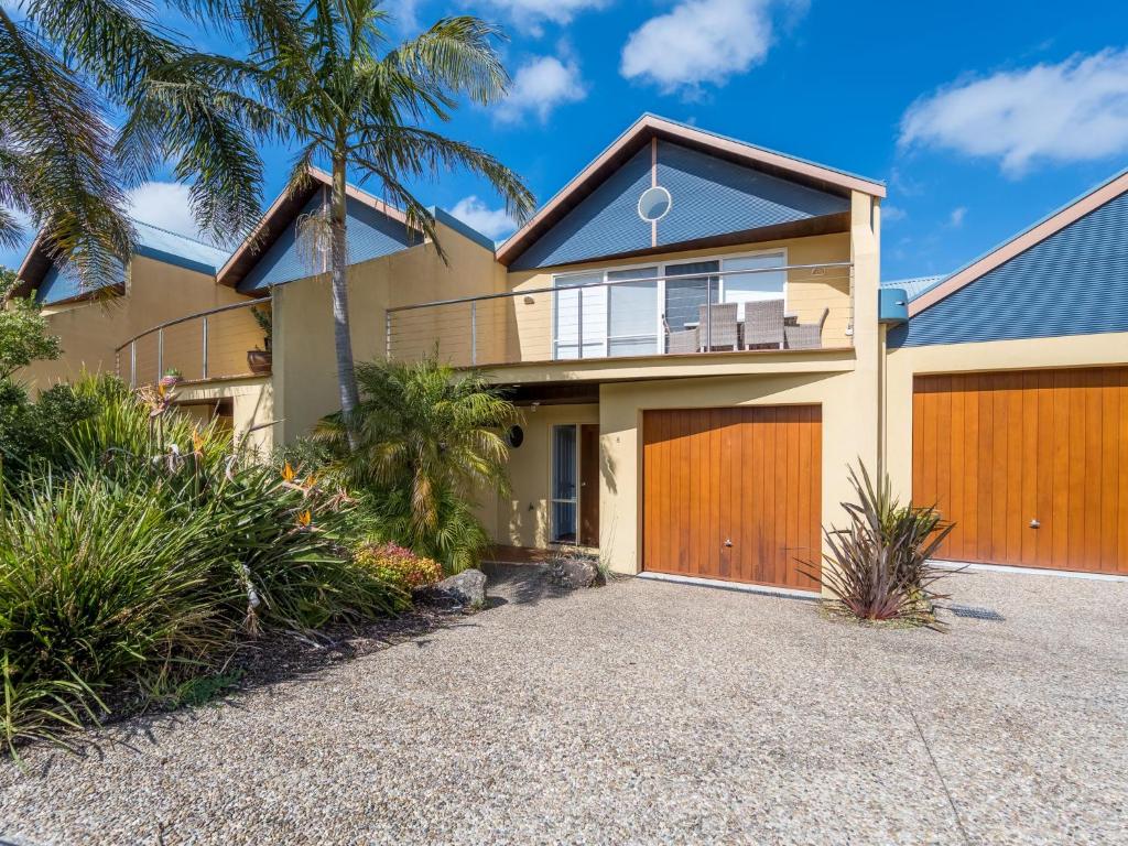 a house with wooden garage doors and palm trees at The Sails 8 Linen and Wifi Included Central Location in Inverloch