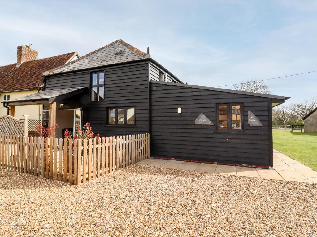 a black house with a fence in front of it at The Cart Lodge in Halstead