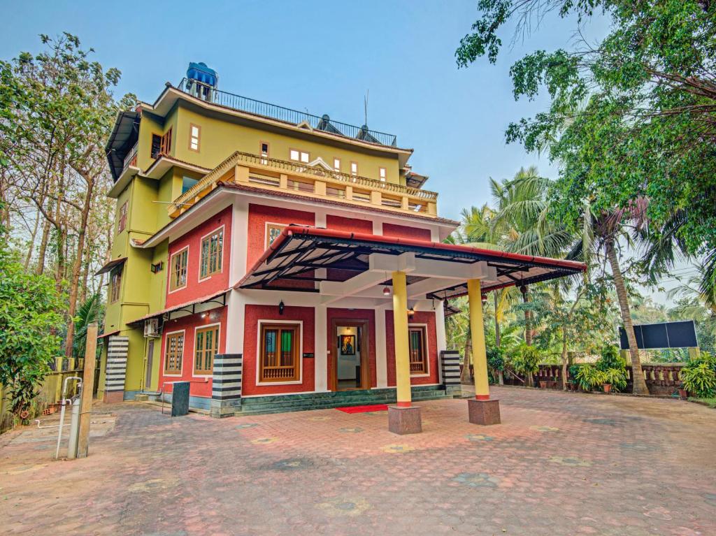 a red and yellow building with a roof at Aaram Beach Resort in Kannur