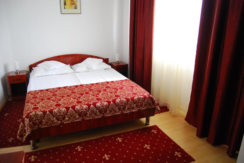 a bedroom with a bed with a red comforter at Dali Hotel in Constanţa