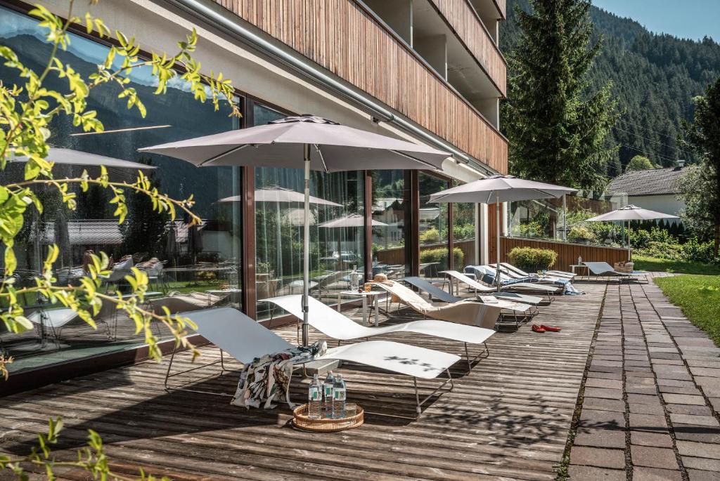 a row of lounge chairs and umbrellas on a deck at Sporthotel Silvretta Montafon in Gaschurn