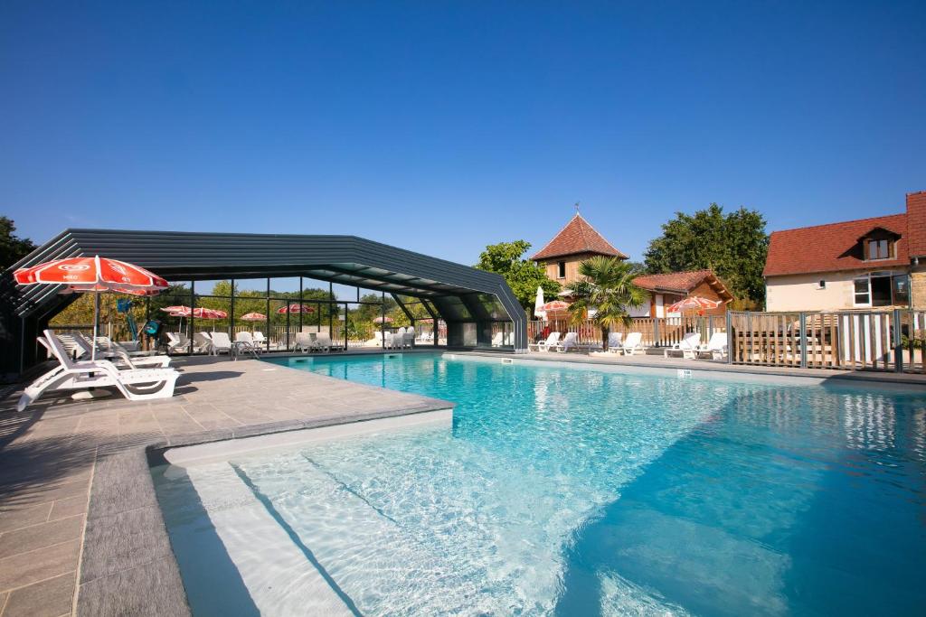 a swimming pool with an umbrella and a chair at Camping Padimadour in Rocamadour