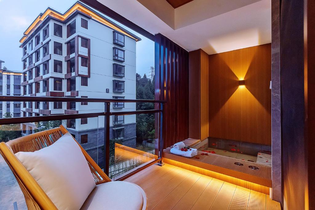 a balcony with a couch and a large window at Mayu Valley Hot Spring Homestay in Tengchong