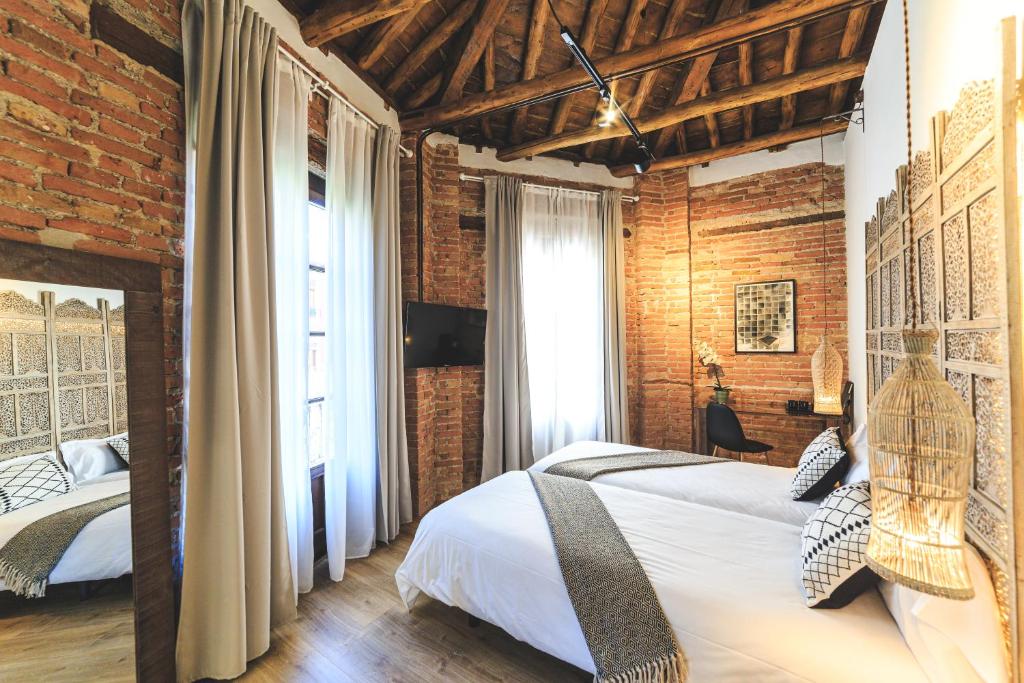 1 dormitorio con 2 camas y pared de ladrillo en Hotel La Casa de Los Mosaicos, en Granada