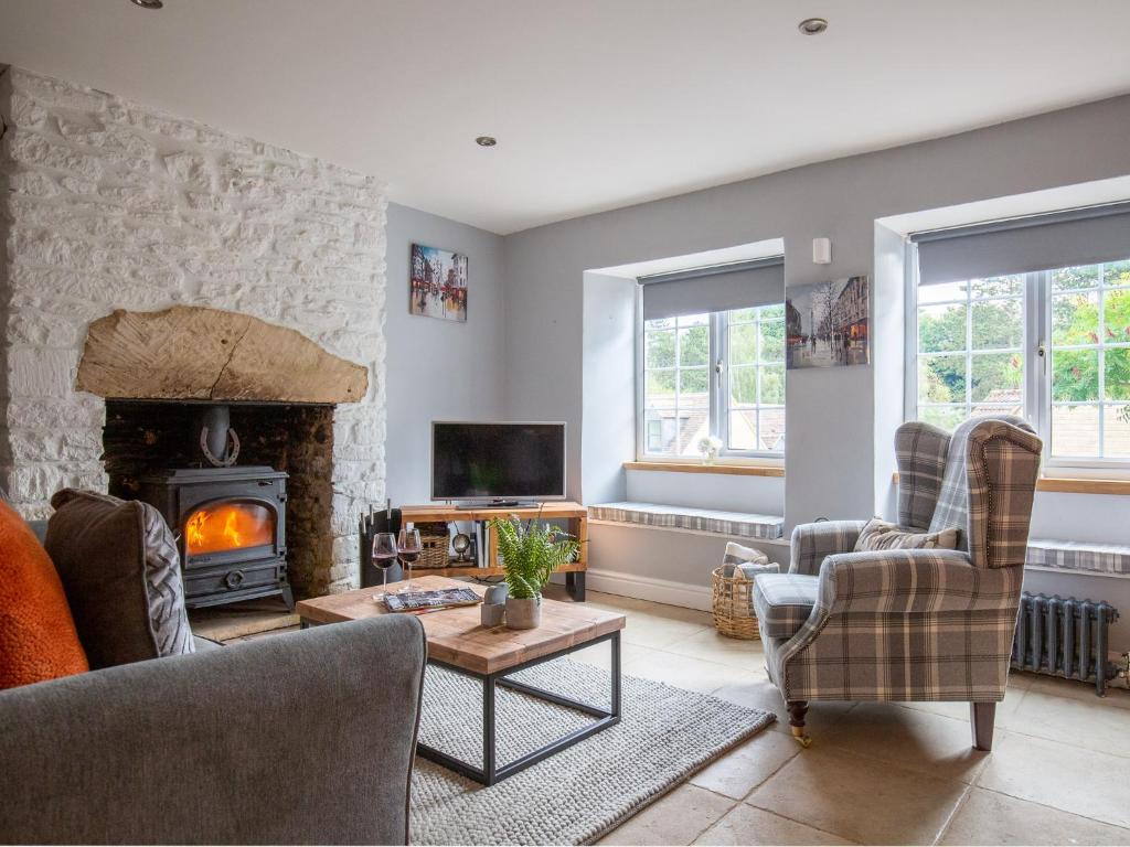 a living room with a fireplace and a tv at Hillside Cottage in Tetbury