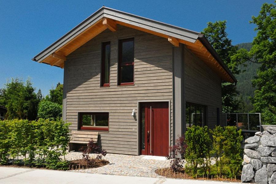 una pequeña casa con una puerta roja en Ferienhaus Alpenflair bei Schliersee en Schliersee