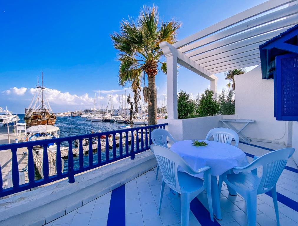een tafel en stoelen op een balkon met uitzicht op het water bij Marina Cap Monastir- Appart'Hôtel in Monastir