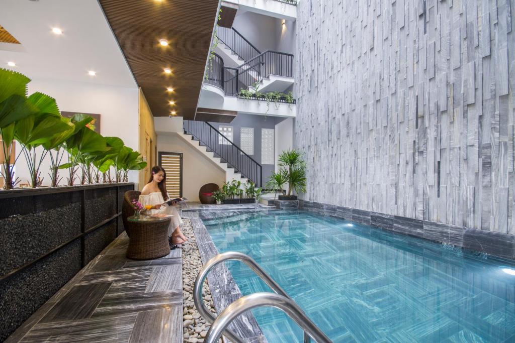 A narrow courtyard pool runs beside a textured wall, planting and an outdoor stairway.