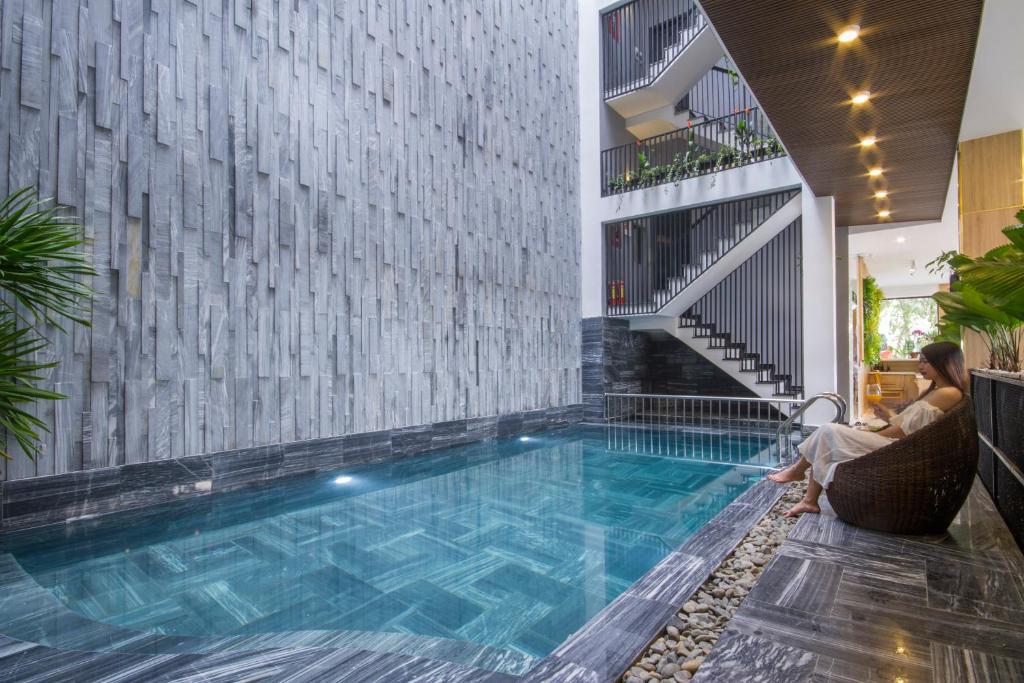 A narrow indoor pool runs alongside a stone-textured wall and open stairwell.