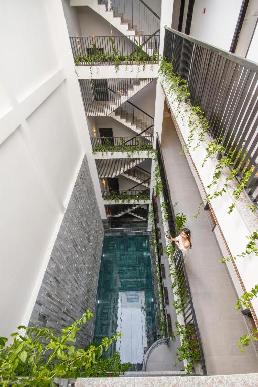 A top-down view reveals a narrow pool enclosed by planted balconies and staircases.
