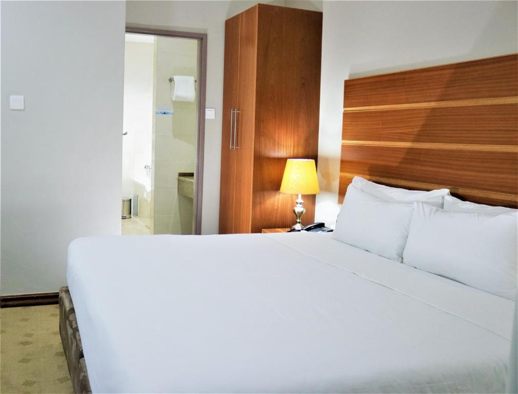 a bedroom with a large white bed and a lamp at Woodlane Hotel in Gaborone
